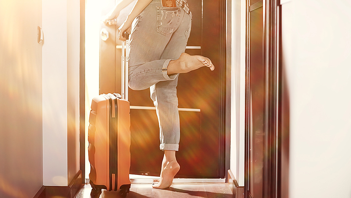A person entering a hotel room with luggage
