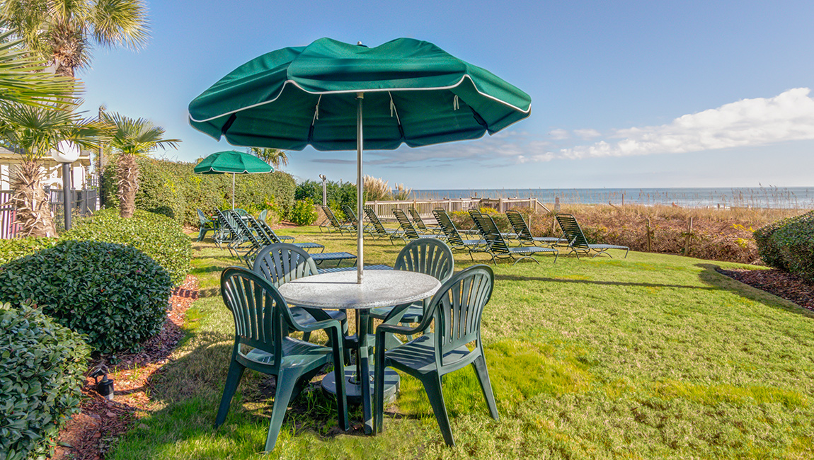 A well-manicured lawn with outdoor seating and ocean views.